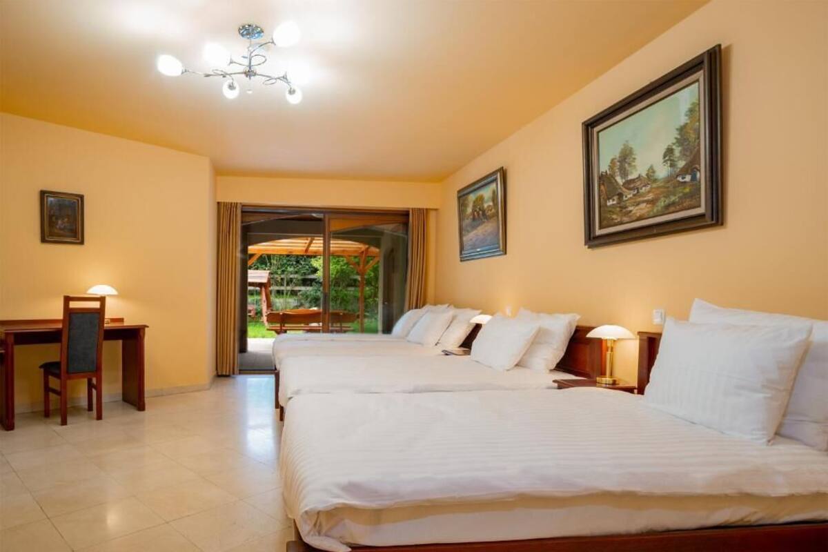 A hotel room with two beds, a desk, and a chair. There is a painting on the wall and a window with curtains.