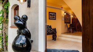 A black sculpture of a bear on a wall, a staircase leading to a room with a blue carpet, and a wooden bench with a painting above it. - La Hacienda  (Vilvoorde)