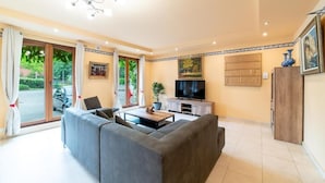 A modern living room with a grey sofa, a coffee table, a TV, and a cabinet. - La Hacienda  (Vilvoorde)