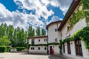 A courtyard with a building featuring a curved facade and ivy-covered walls. - La Hacienda (Vilvoorde)