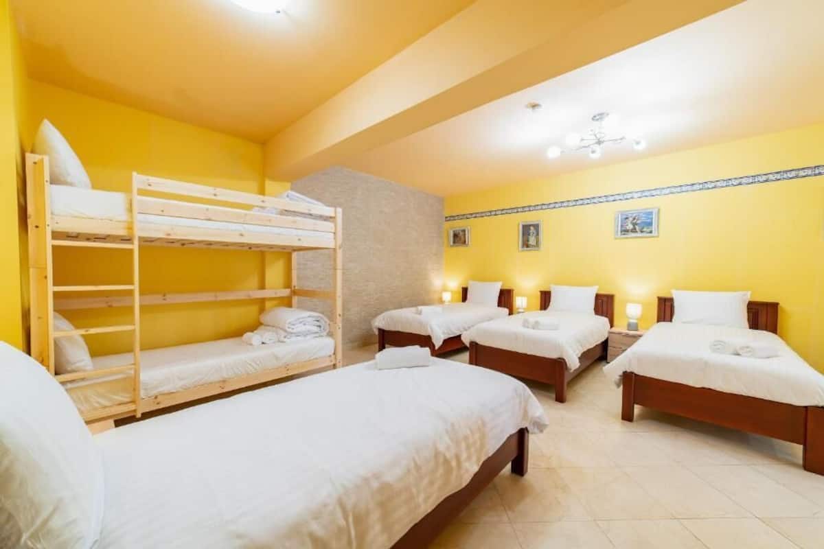 A room with four beds, two of which are bunk beds, and a small staircase.