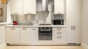 Een moderne keuken met witte kastjes, een roestvrijstalen afzuigkap, een magnetron en een inbouwoven.