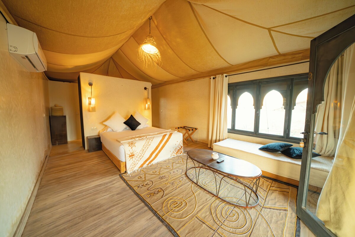 A bedroom with a bed, bedside table, and a window with a view.