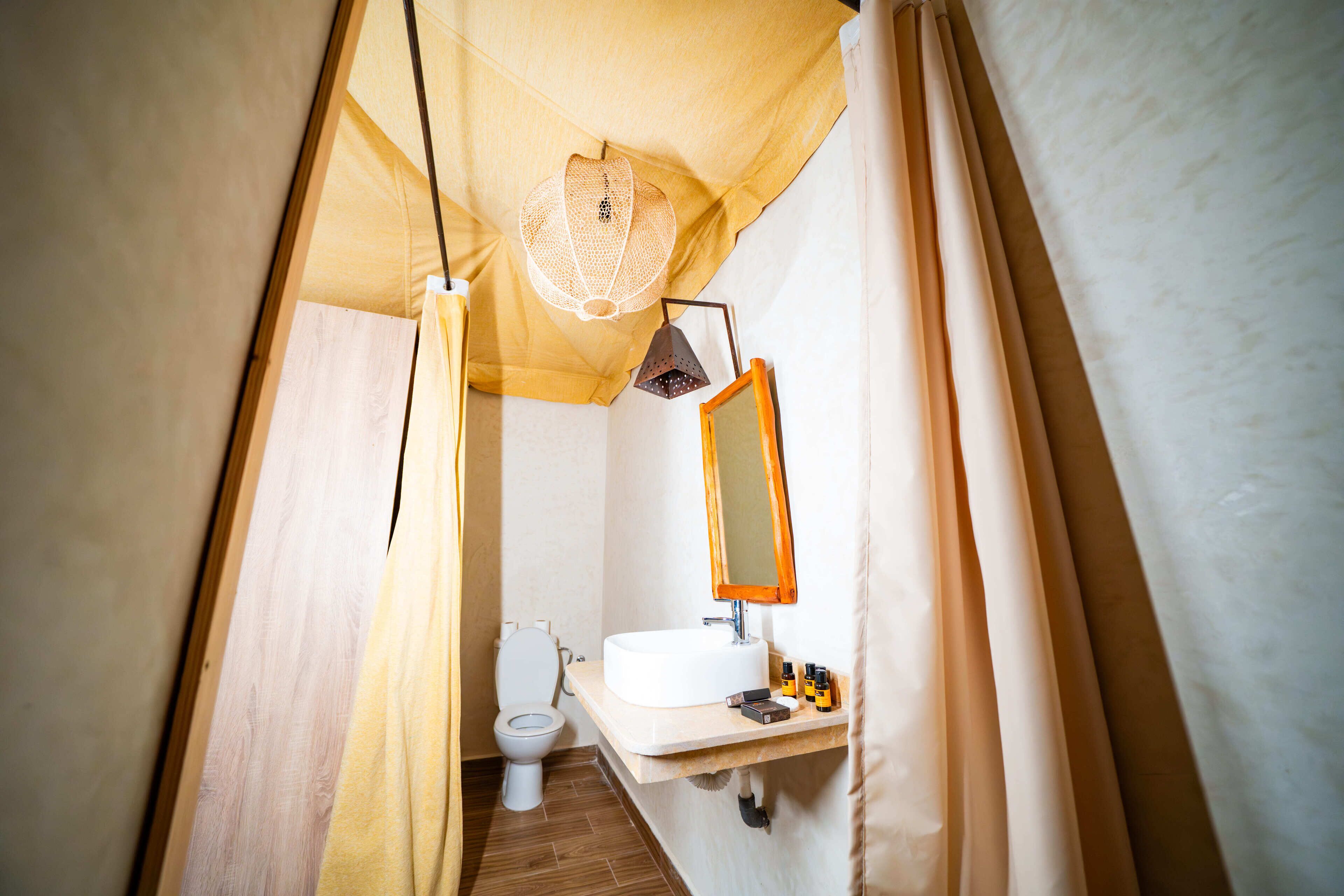 A narrow bathroom with a toilet, sink, and mirror.