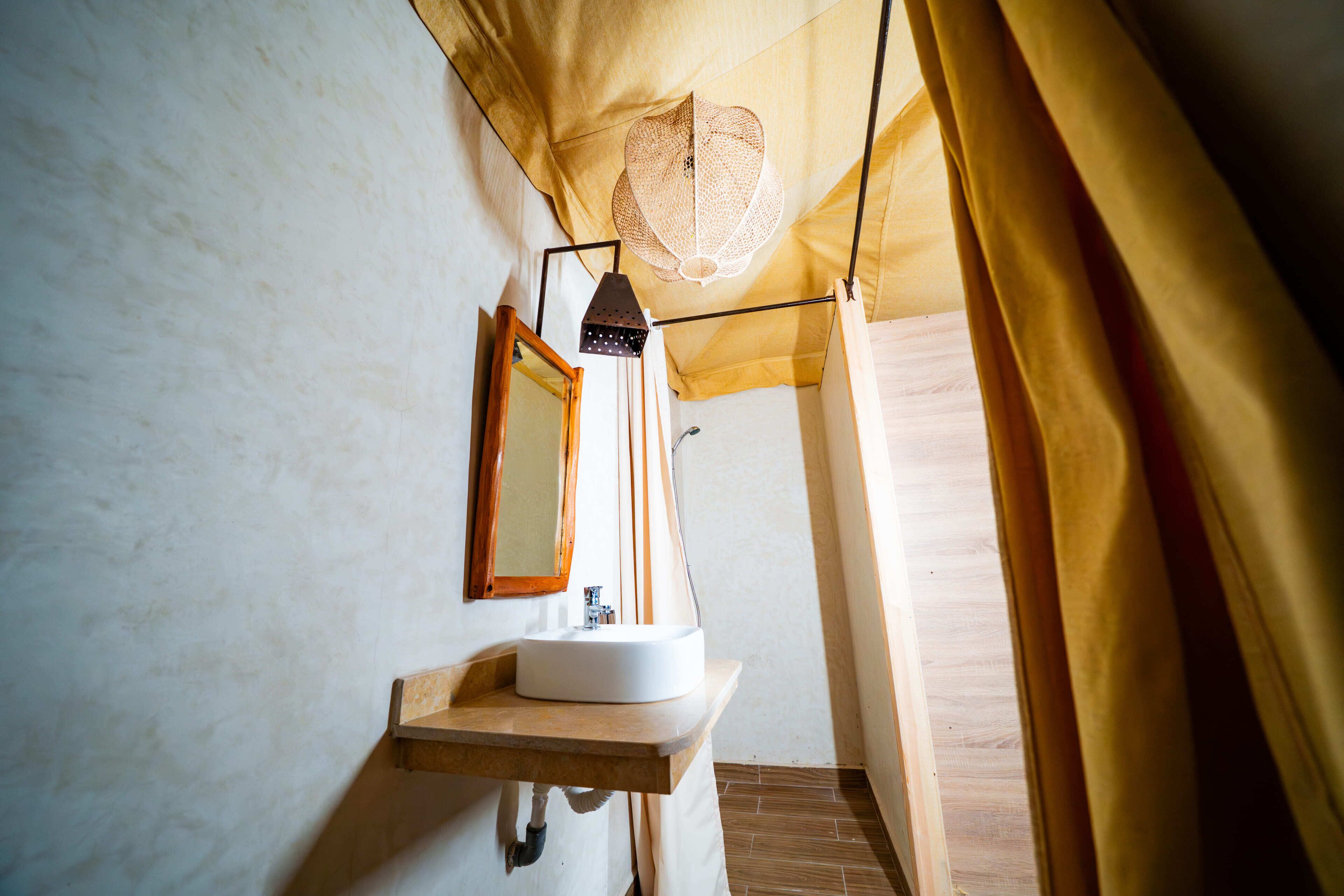 Un baño pequeño con tocador de madera, lavamanos blanco, espejo y lámpara colgante.
