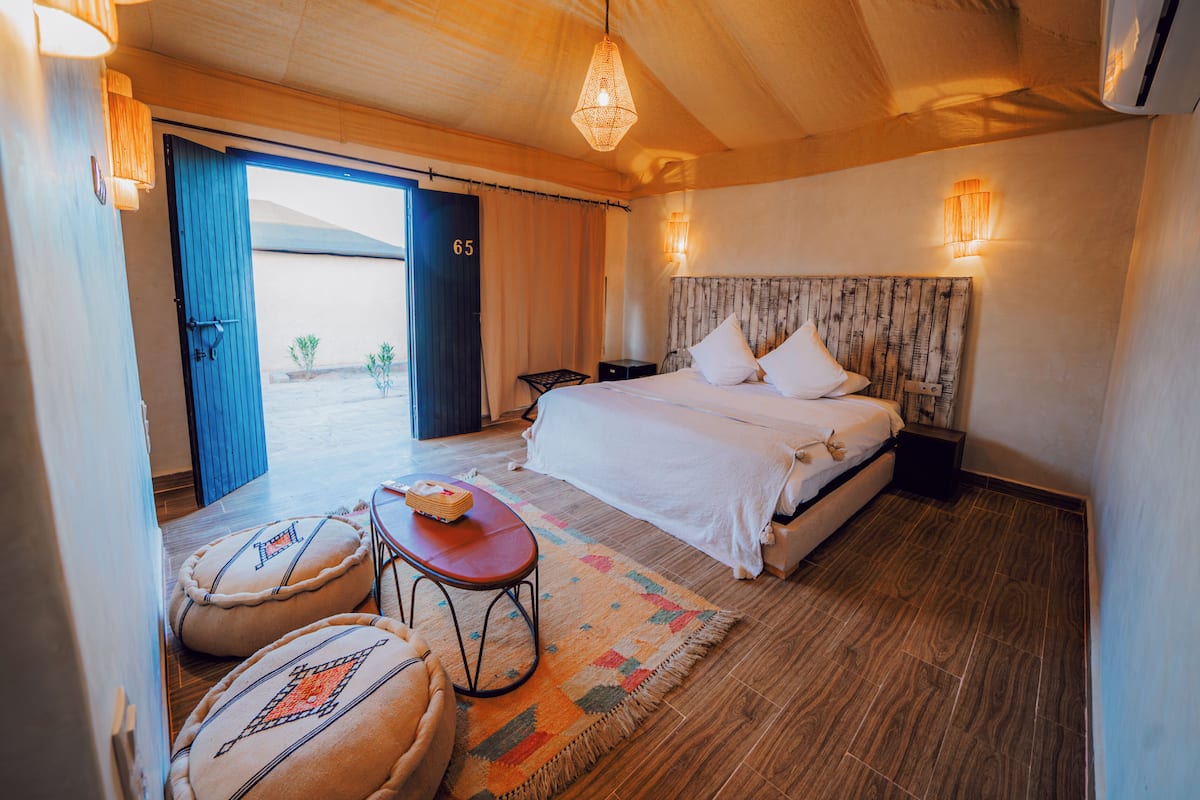 A bedroom with a bed, bedside table, and a view of the outside.