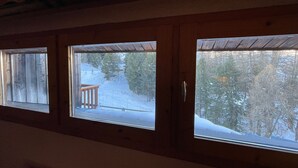 Quarto com três janelas com vista para uma paisagem nevada.