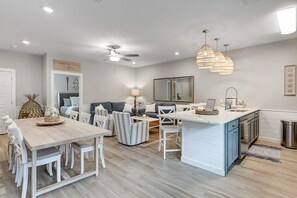 Una cocina moderna con una isla central, muebles blancos y un comedor con una mesa y sillas de madera.