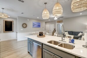 Una cocina moderna con una isla grande, electrodomésticos de acero inoxidable y una zona de comedor con sofá gris.