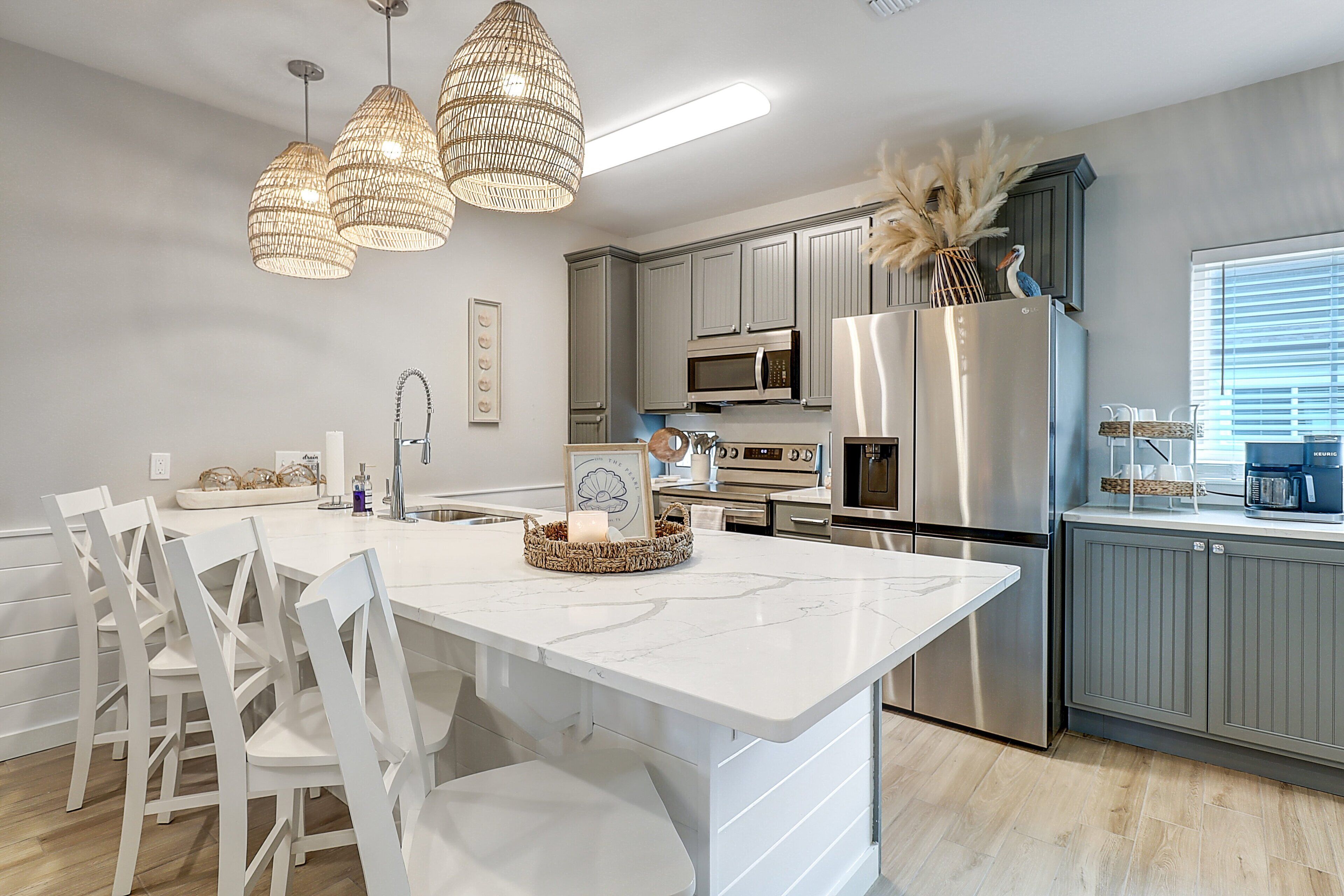 A modern kitchen with white cabinetry, stainless steel appliances, and a central island with seating.
