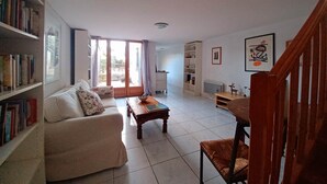 A living room with a sofa, a coffee table, a bookshelf, and a dining area with a table and chairs. - Small oasis in the center of Céret (Céret)