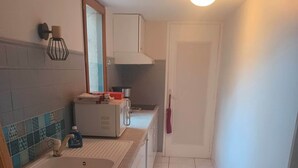 A compact kitchen with white cabinets, a double sink, and a microwave. - Small oasis in the center of Céret (Céret)