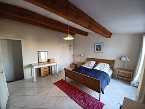 A bedroom with a bed, bedside tables, a desk, a chair, and a hanging light fixture. - Small oasis in the center of Céret (Céret)