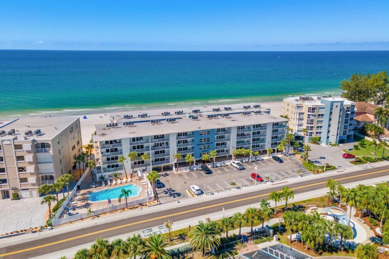 A hotel with a pool, parking, and a view of the ocean.