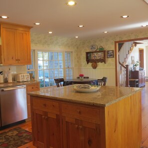 A kitchen with wooden cabinets, a built-in island, and a dining area with a table and chairs.