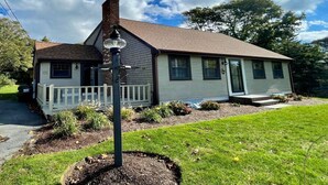 A single-story house with a front porch, a chimney, and a well-maintained lawn. - Dog friendly home with large backyard! (North Chatham)