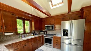 A kitchen with wooden cabinets, stainless steel appliances, granite countertops, and a skylight. - Dog friendly home with large backyard! (North Chatham)