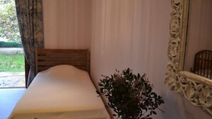 A bedroom with a bed, a vase with plants, and a mirror with ornate frame. - Platanus Gardenhouse (Saronikos)