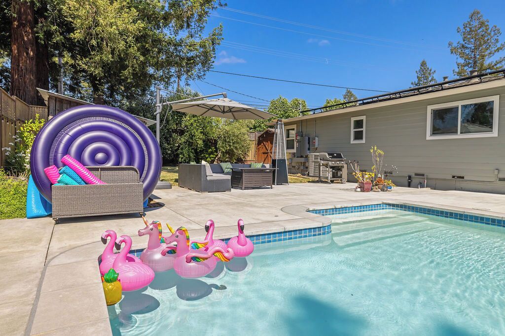Ein Garten mit Swimmingpool, aufblasbaren Flamingos und einem großen Schwimmreifen.
