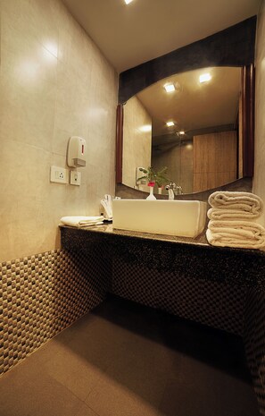 Un baño moderno con un espejo grande, un lavamanos y un perchero para toallas.