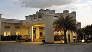 A building with a central entrance, columns, and a paved courtyard. - TreeHouse Sunrise Resort & Caravan Park (Neemrana)