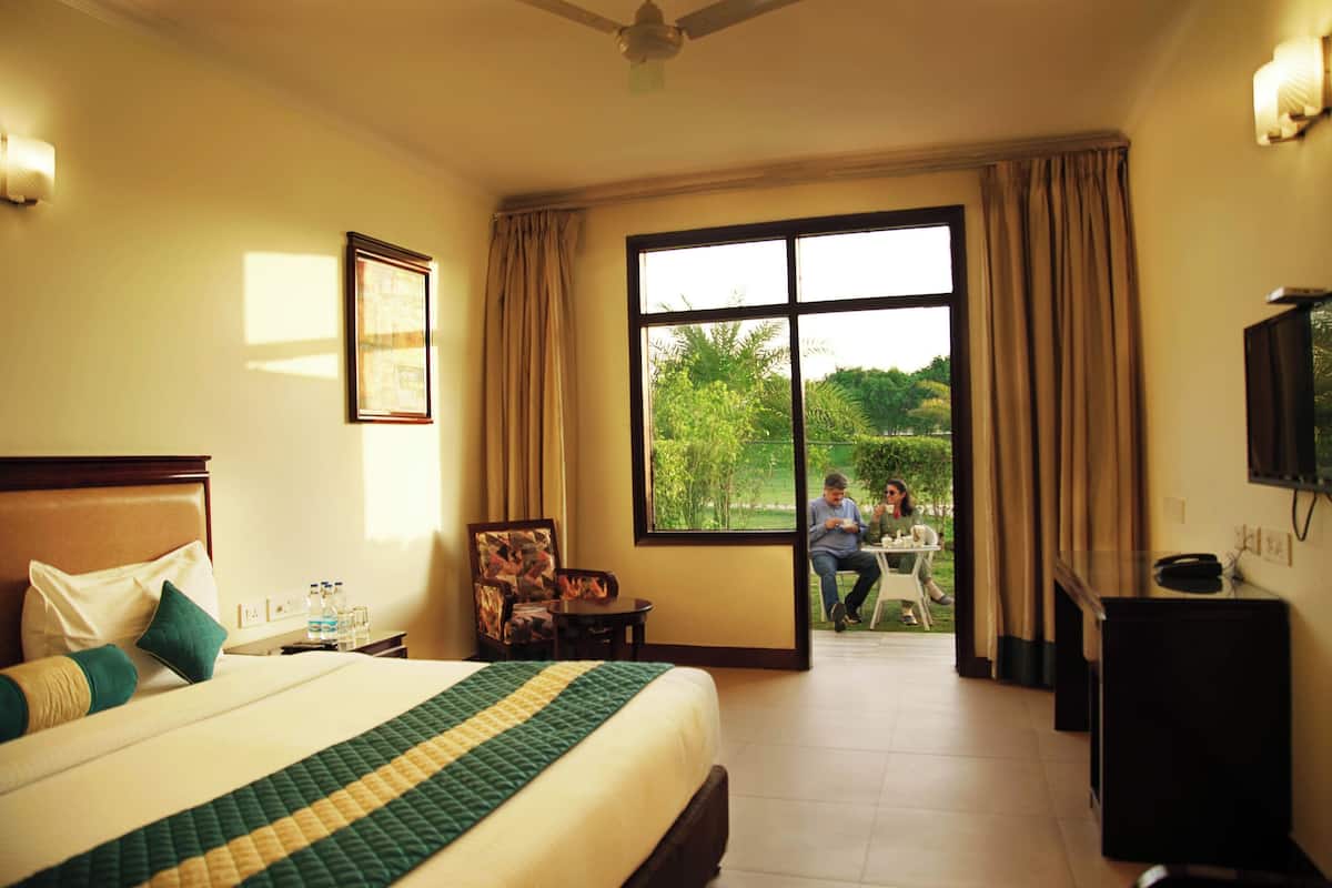 A hotel room with a large bed, a chair, a desk, and a television.