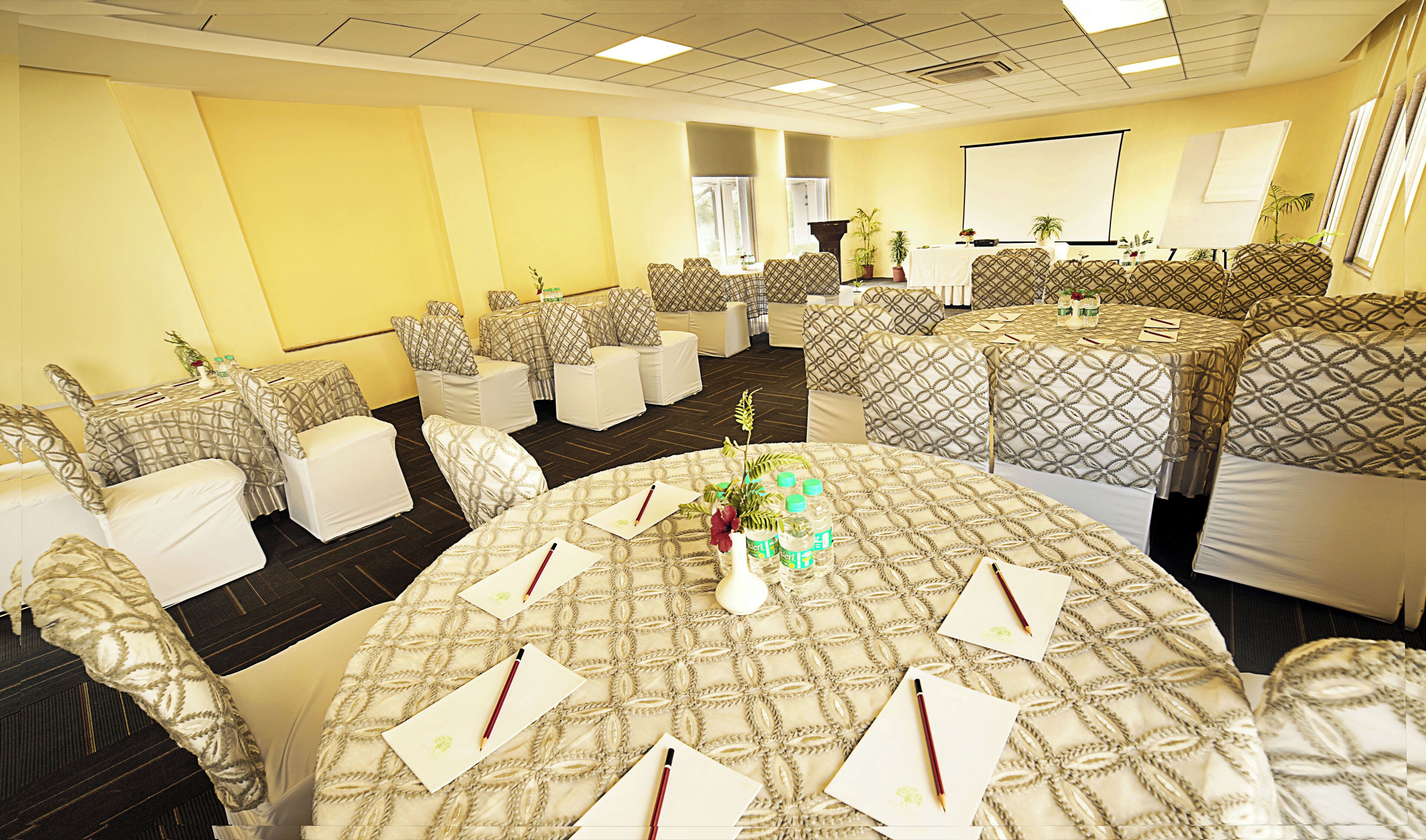 A conference room with round tables, chairs, and a projector screen.