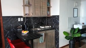 A kitchen with a marble backsplash, wooden cabinets, a red chair, and a potted plant. - Catherine Suites (Willemstad)