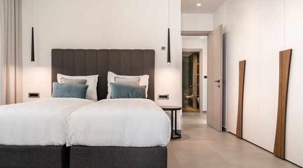 A modern bedroom with a large bed, bedside tables, and a walk-in closet. - Balia Suites (Corfu)