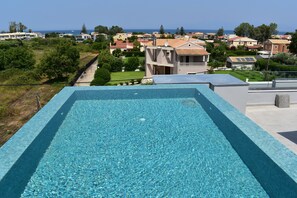 Una piscina al aire libre de temporada, sombrillas