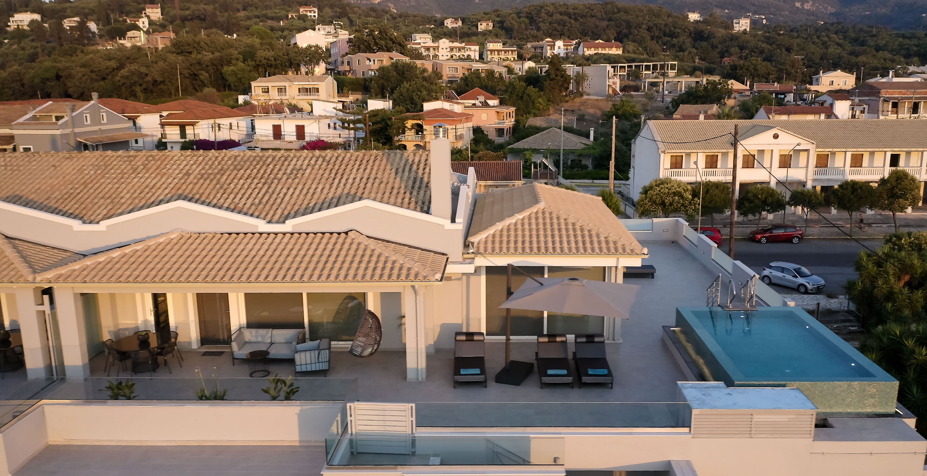 Ein Wohngebäude mit Pool auf dem Dach, einer überdachten Terrasse mit Sitzgelegenheiten und Blick auf die umliegende Nachbarschaft.