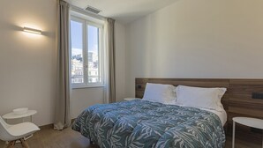 A bedroom with a bed, a chair, a small table, and a window with curtains. - Brignole de Ferrari - 401 by Wonderful Italy (Genova)