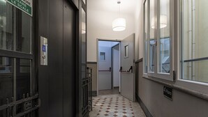 A hallway with a tiled floor, a door with a sign, and a window with a view. - Brignole de Ferrari - 401 by Wonderful Italy (Genova)