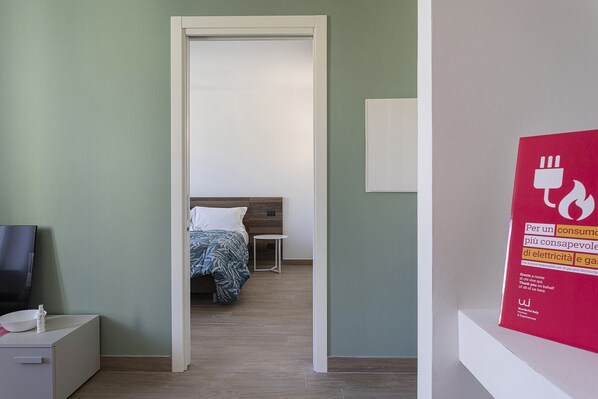 Una habitación de hotel con una cama, una mesita pequeña y un televisor sobre un mueble.