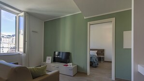 A modern living room with a sofa, a flat-screen TV, and a dining area with a table and chairs. - Brignole de Ferrari - 401 by Wonderful Italy (Genova)