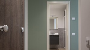 Pasillo que conduce a un baño con lavamanos y espejo.