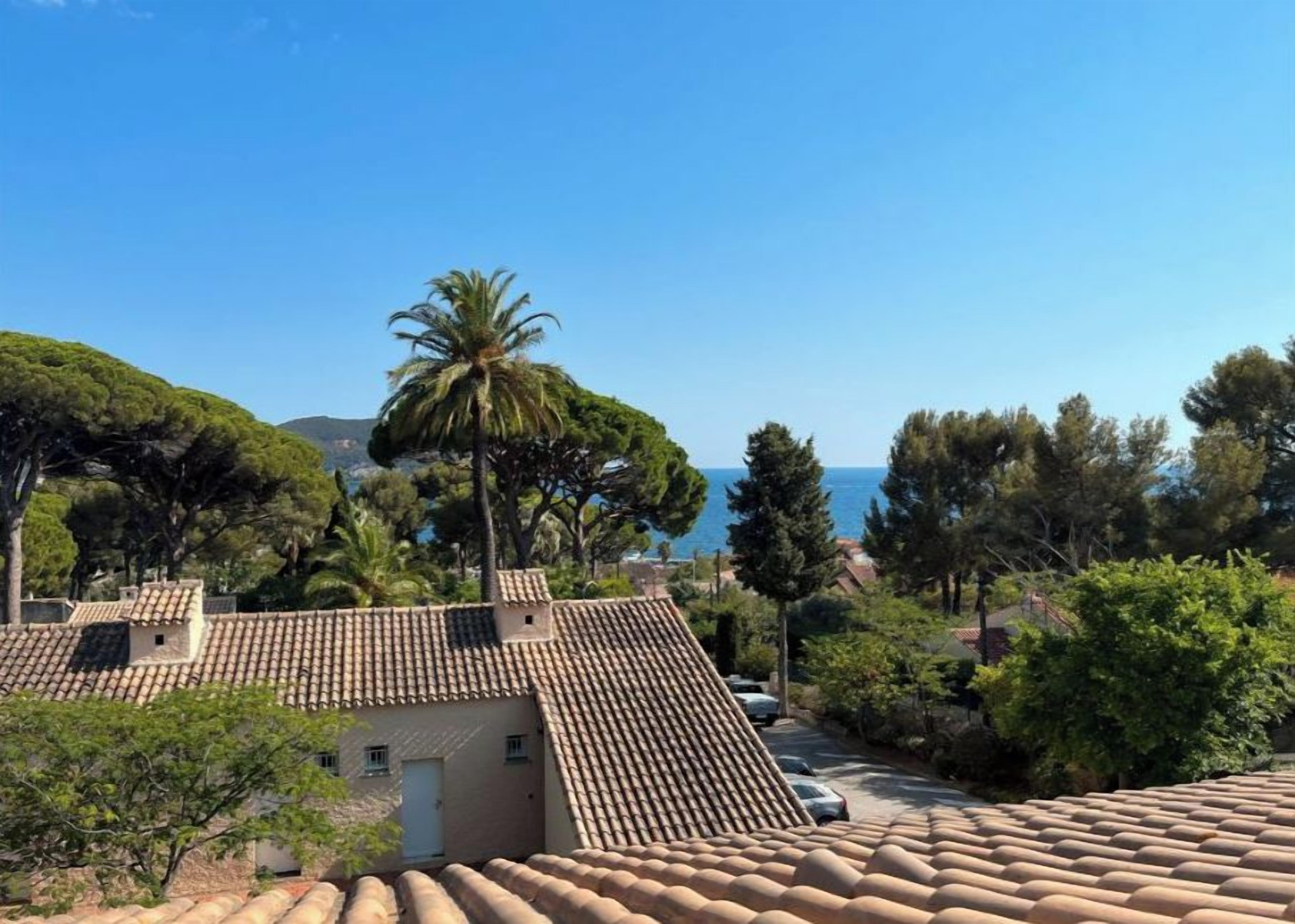 A Mediterranean-style building with terracotta roof tiles, surrounded by lush greenery and a clear blue sky.