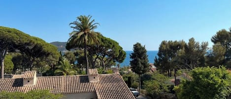 A Mediterranean-style building with terracotta roof tiles, surrounded by lush greenery and a clear blue sky.
