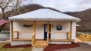 Eine kleine, eingeschossige Hütte mit Veranda, Fußmatte und einer amerikanischen Flagge.