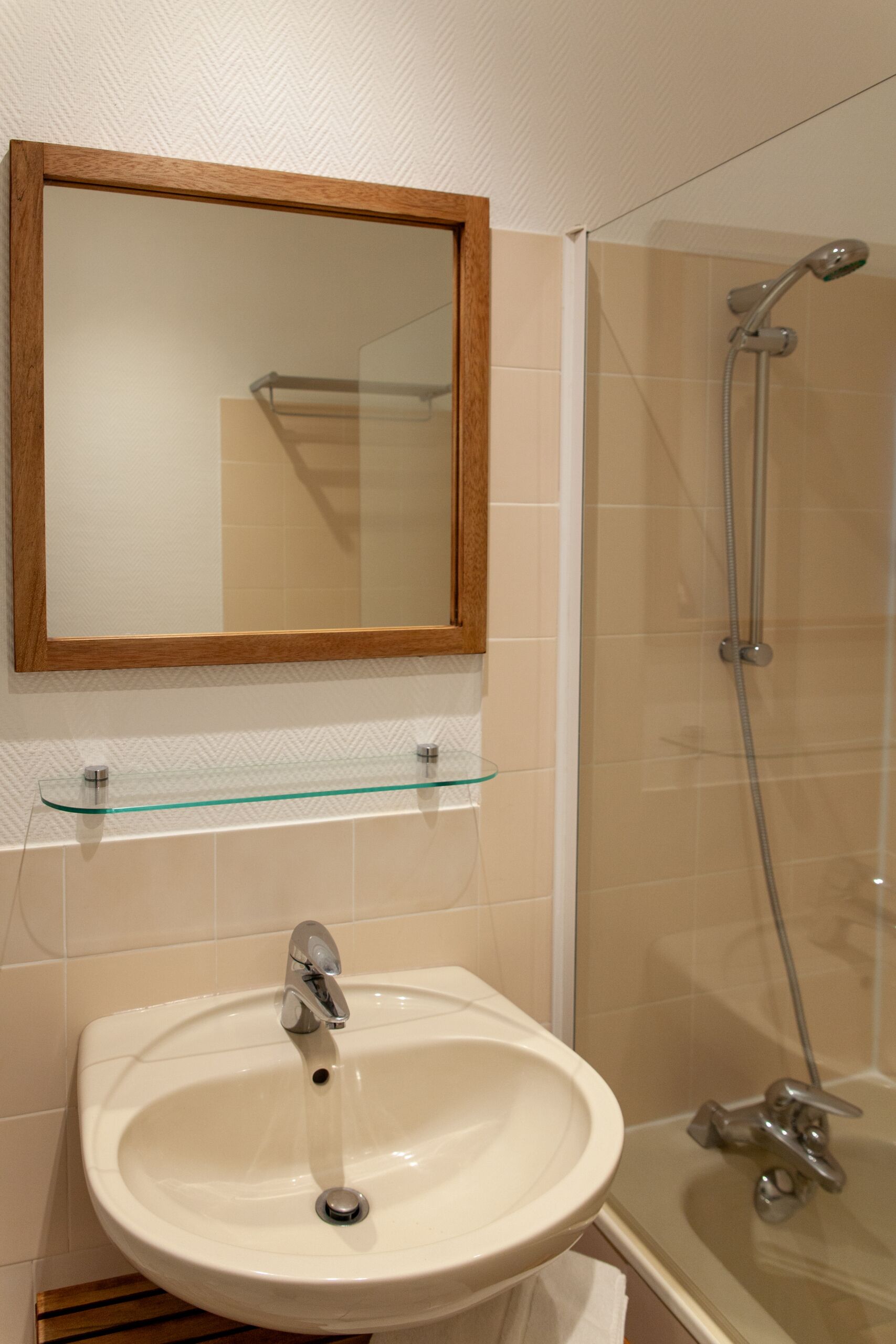 A bathroom with a sink, mirror, and shower.