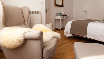 Une chambre à coucher avec un lit, une chaise dotée d’un coussin moelleux, une petite table avec un miroir et un radiateur.
