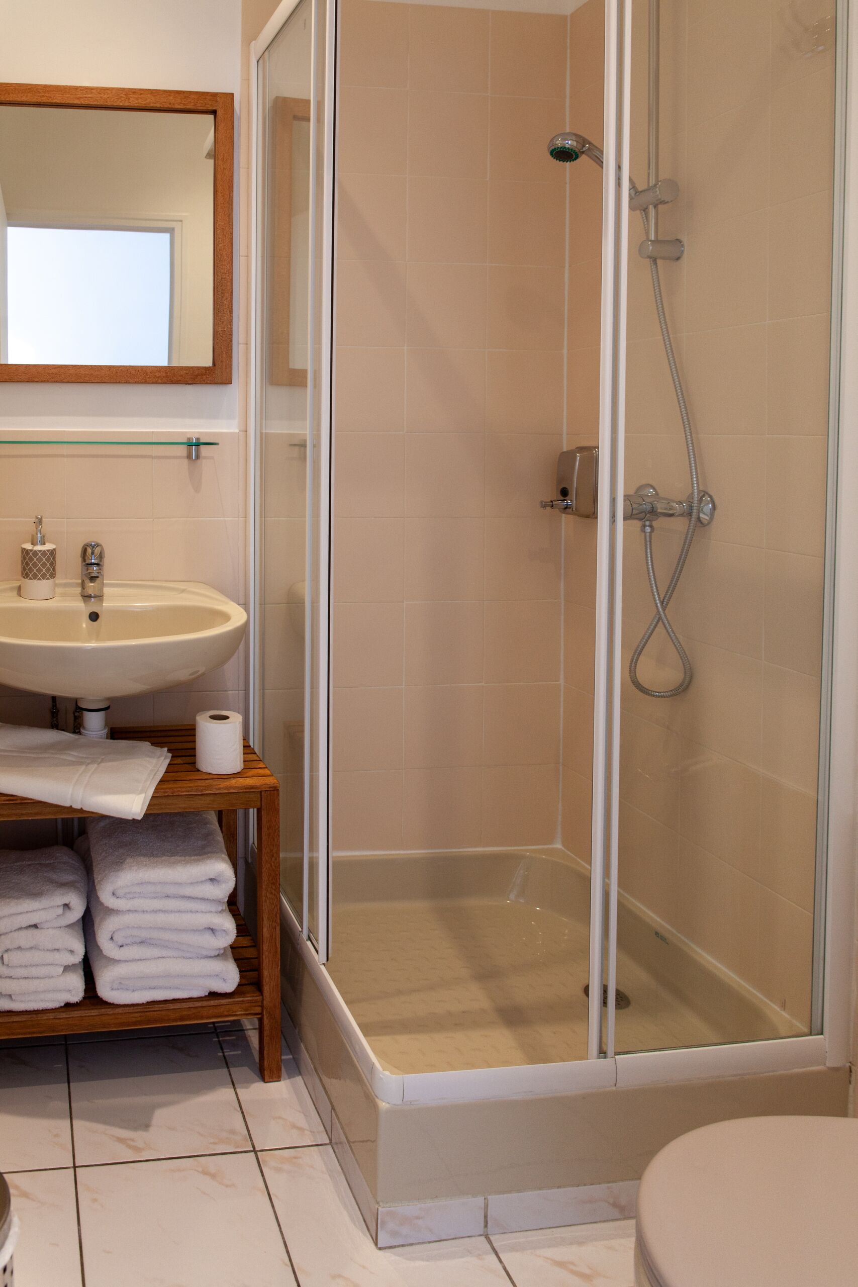 A bathroom with a glass-enclosed shower, a sink, and a mirror.