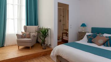 Une chambre à coucher avec un lit, une chaise, une plante et une porte de salle de bain.