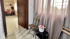 Ein Flur mit einer Holztür, einem Klappsessel, einem kleinen Tisch mit Blumenvase und einer Bank.