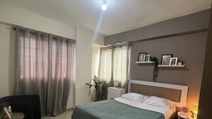 Ein modernes Hotelzimmer mit einem großen Bett, einem kleinen Schreibtisch, einem Stuhl und einem Nachttisch mit Lampe.