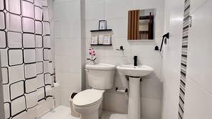 Ein Badezimmer mit Toilette, Waschbecken und Duschbereich.