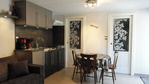 Una cocina compacta con electrodomésticos modernos, un comedor con mesa y sillas, y un sofá.