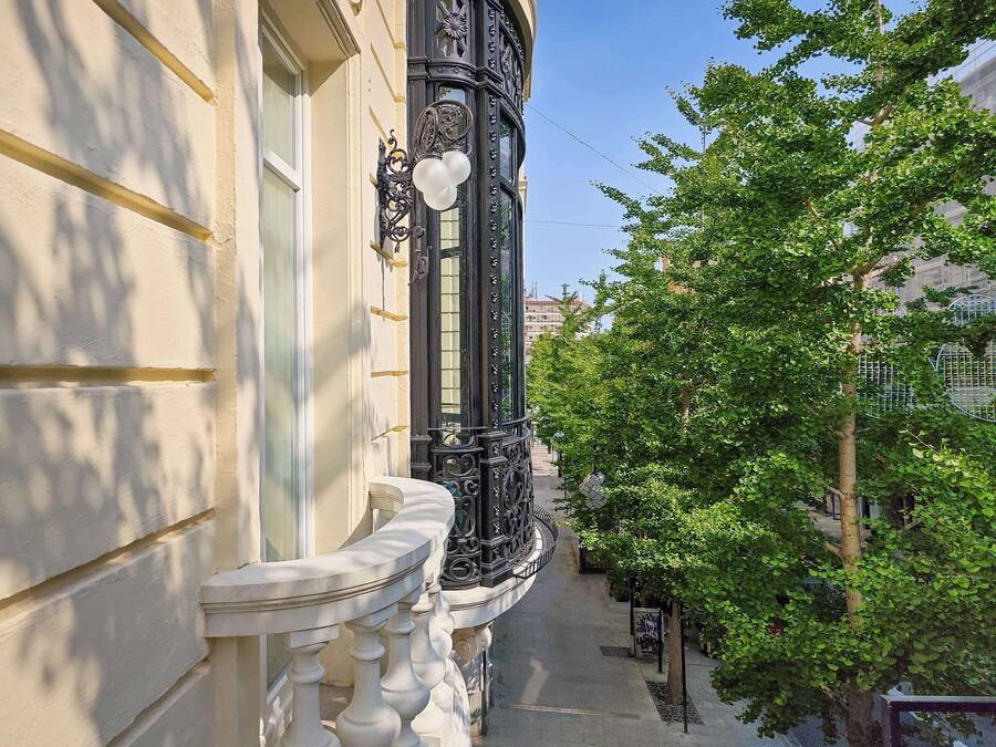 A narrow balcony with ornate black railings and a white balustrade.