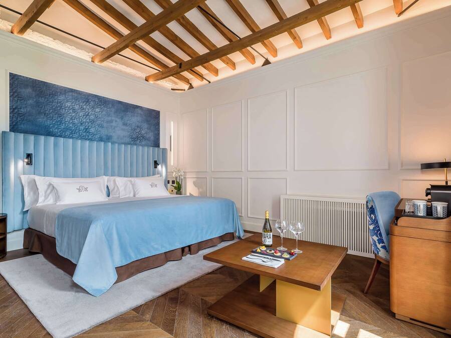Une chambre d’hôtel moderne avec un grand lit, une table basse en bois, une table de chevet et une commode.