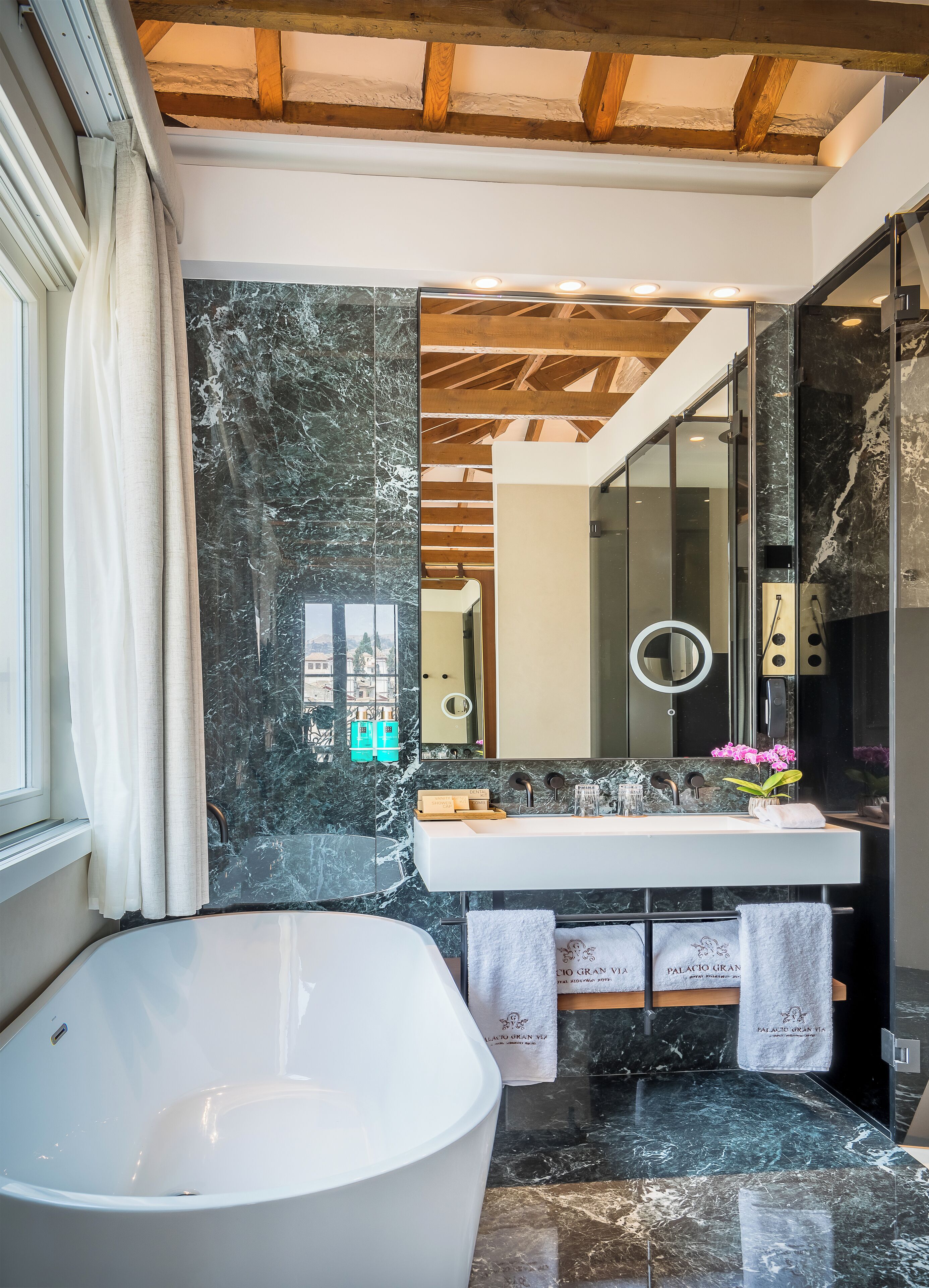 A modern bathroom with a freestanding bathtub, a marble vanity, and a large mirror.